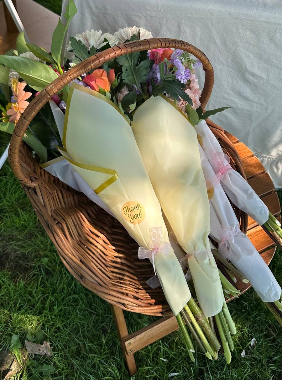Wrapped bouquets resting in a wicker basket on the grass