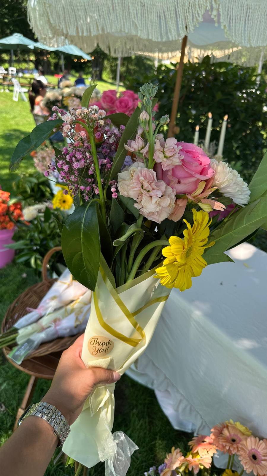 A finished bouquet in a cream wrap with a thank-you sticker