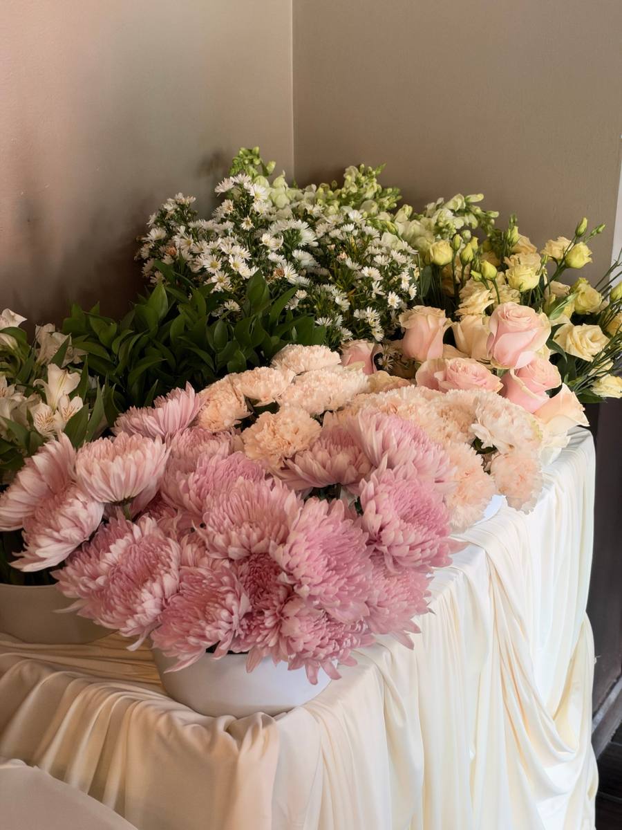 Blush spider mums, peach carnations, and pink roses on a draped ivory table