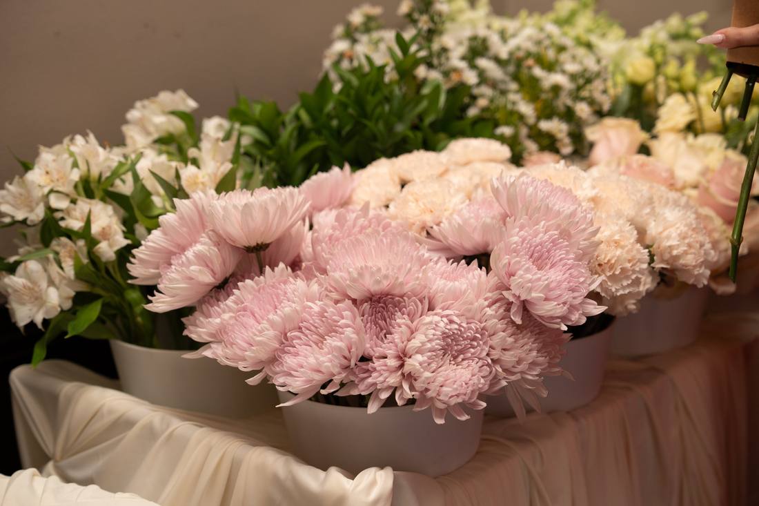 Pink spider mums, peach carnations, and white alstroemeria in ivory pots