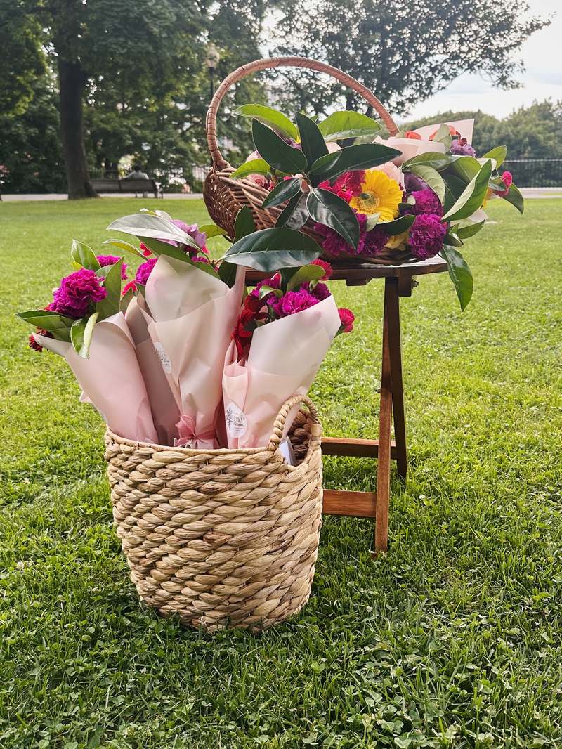 Baskets of wrapped Sunday Blooms bouquets at a park pop-up