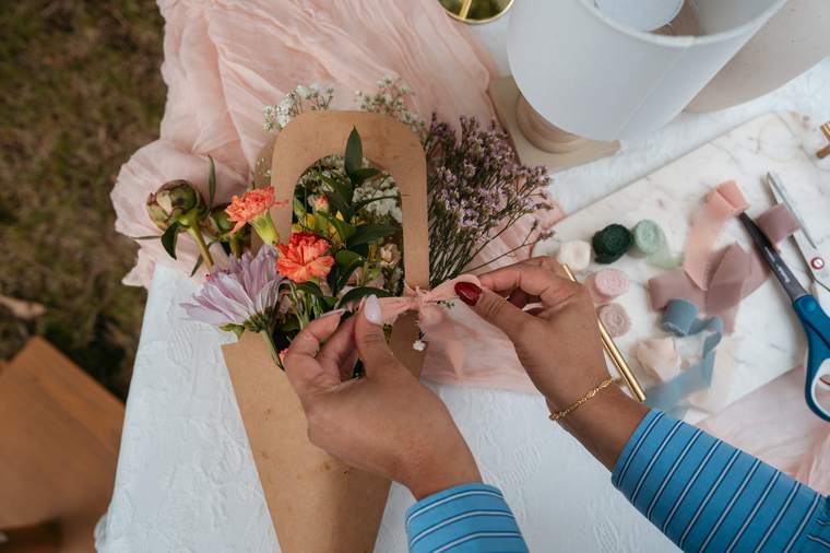 Hands tying a ribbon around a finished bouquet