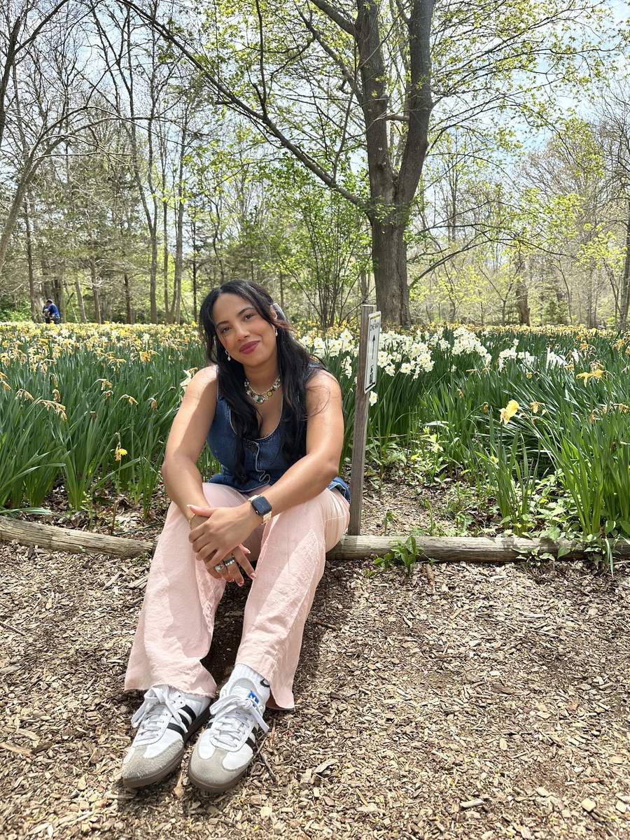 Pri, owner of Sunday Blooms, sitting in front of a field of daffodils